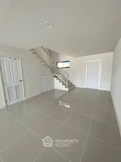 Spacious modern living room with sleek tiled flooring and elegant staircase