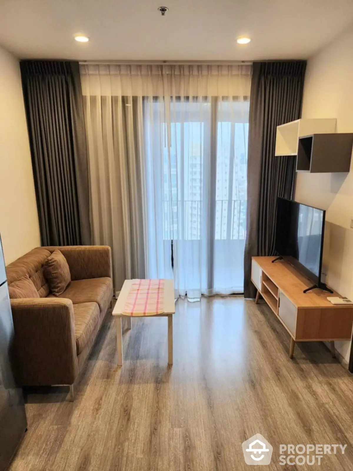 Modern living room with cozy sofa, TV, and large window view.