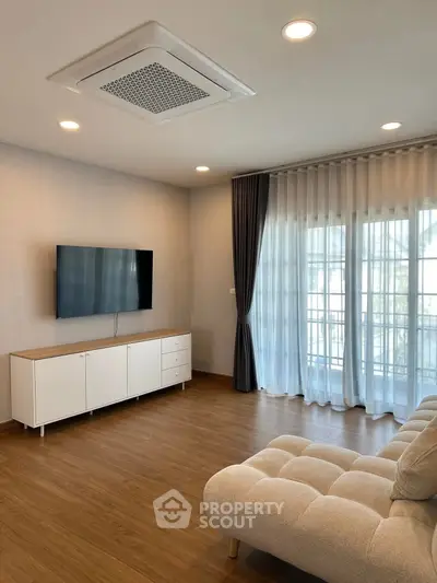 Modern living room with sleek TV setup and elegant curtains, perfect for relaxation and entertainment.