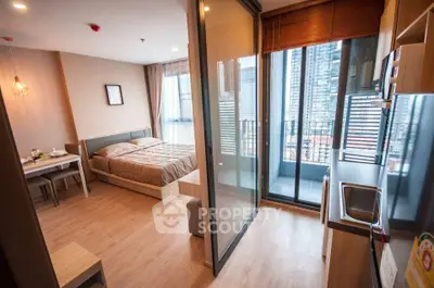 Modern studio apartment with open layout and city view balcony, featuring cozy bedroom and sleek kitchen.