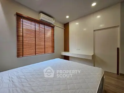 Modern bedroom with sleek design, featuring built-in wardrobe and large window with wooden blinds.