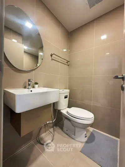 Modern bathroom with sleek design and round mirror in a contemporary apartment.