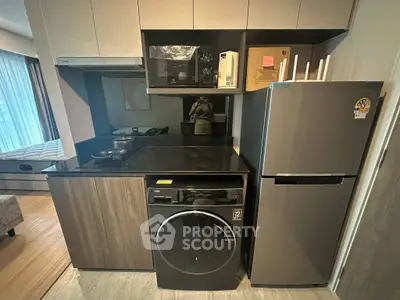 Modern kitchen with sleek appliances and washing machine in compact layout.