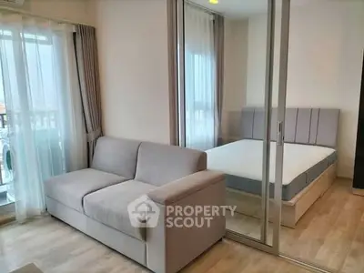 Modern apartment with cozy living room and bedroom separated by glass doors.