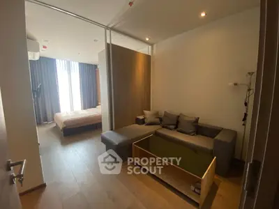 Modern apartment with cozy living room and bedroom, featuring sleek wooden flooring and contemporary furniture.