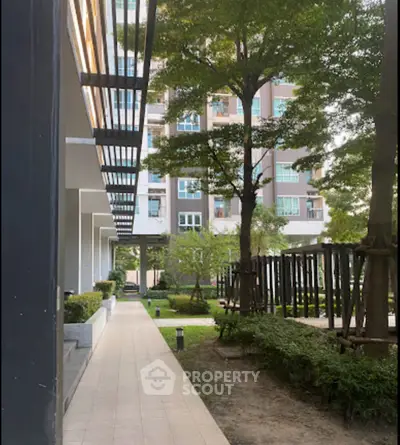 Modern apartment building with lush garden and walkway, perfect for urban living.