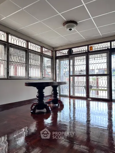 Spacious room with polished wooden floors and large windows, perfect for natural light.