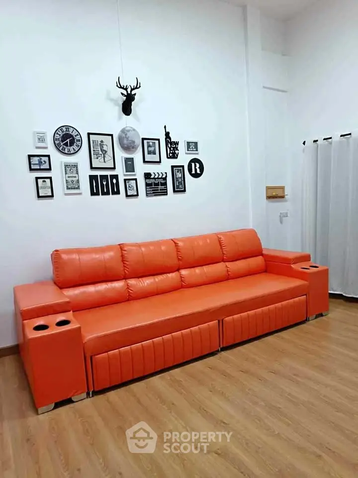 Modern living room with vibrant orange sofa and stylish wall decor, perfect for contemporary urban living.