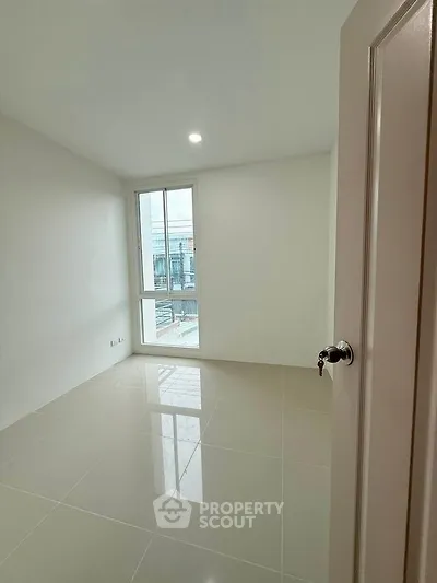 Bright and spacious empty room with large window and glossy tiled floor, perfect for customization.
