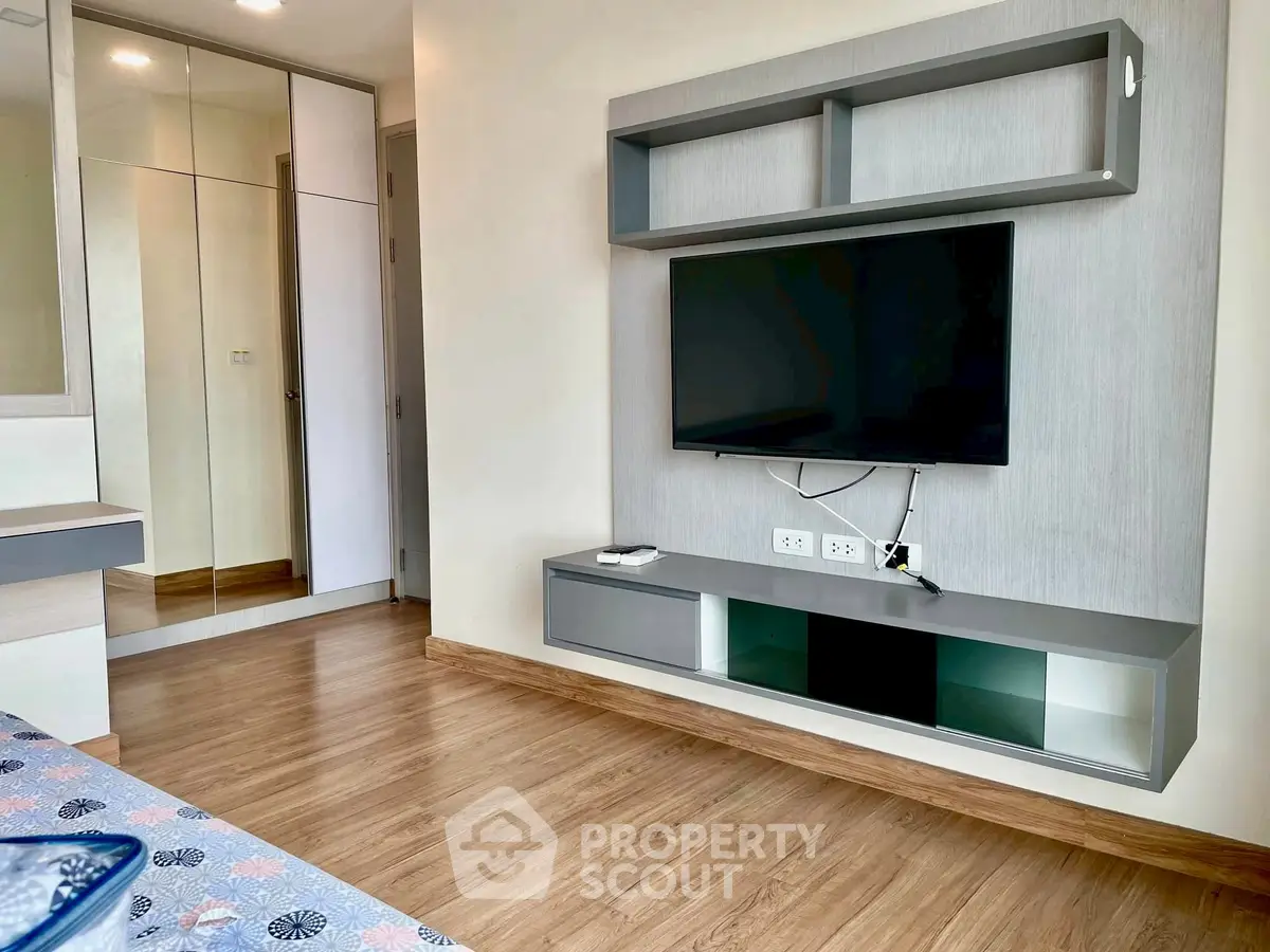 Modern bedroom with wall-mounted TV and wooden flooring