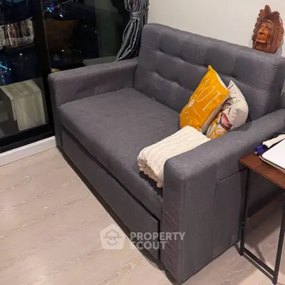 Cozy living room with modern gray sofa and decorative pillows, perfect for relaxation.