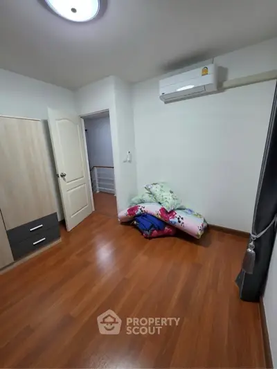 Spacious bedroom with wooden flooring and air conditioning, perfect for comfort and relaxation.