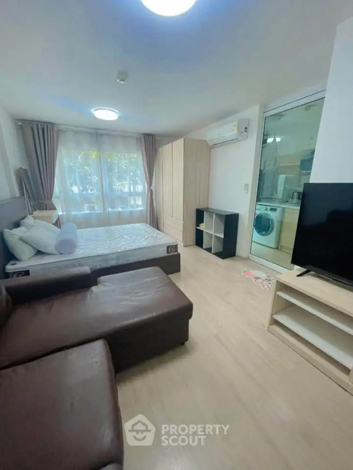 Modern studio apartment with cozy living area and large window, featuring a comfortable bed and sleek furniture.