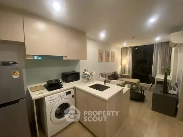 Modern open-layout kitchen and living room with washing machine and stylish decor.