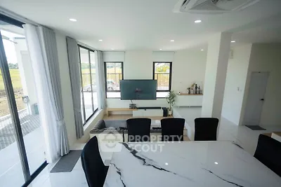 Spacious modern living room with large windows and elegant dining area, perfect for family gatherings.