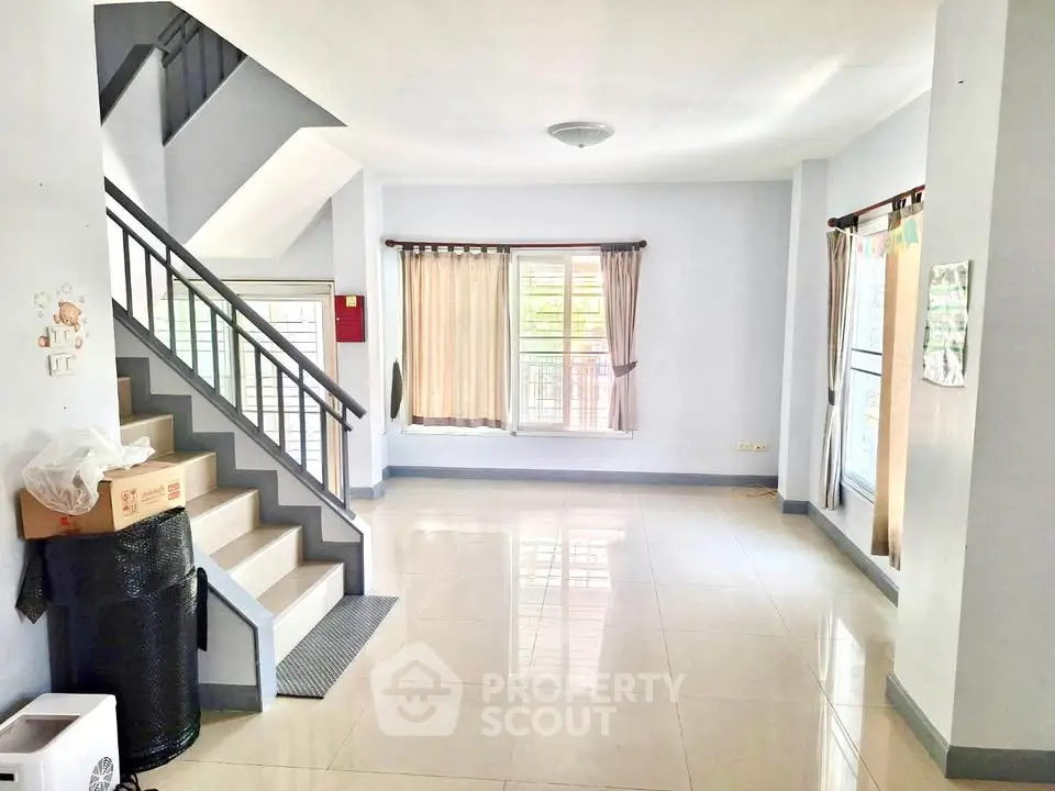 Spacious and bright living room with staircase and large windows in modern home.