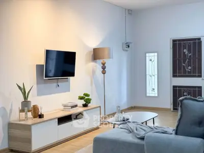 Modern living room with stylish decor and wall-mounted TV, featuring cozy seating and elegant lighting.