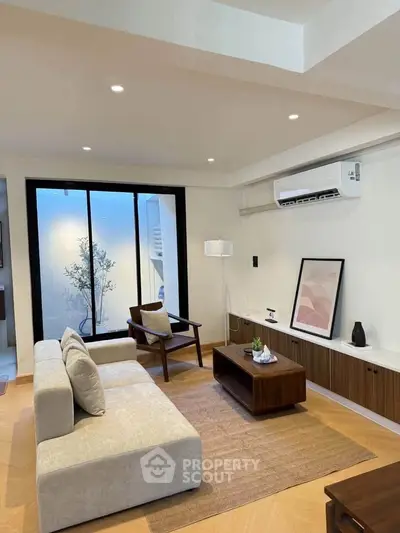 Modern living room with stylish furniture and large window offering natural light.