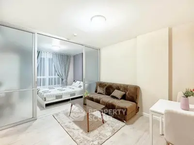 Modern studio apartment with cozy living area and bedroom separated by sliding glass doors.