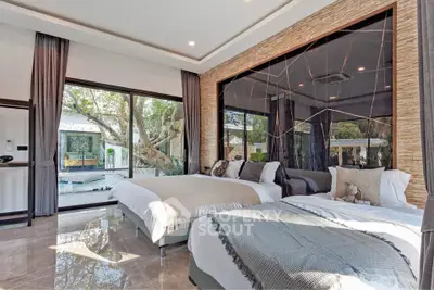 Luxurious bedroom with large windows overlooking a serene garden and pool area, featuring elegant decor.