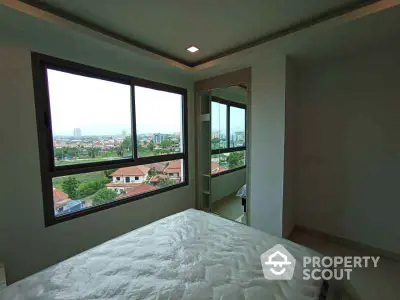 Spacious bedroom with large window offering stunning city views in modern apartment.