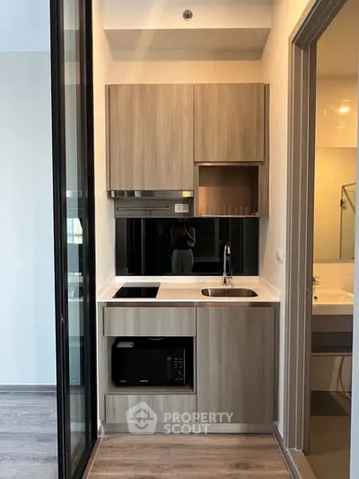 Modern compact kitchen with sleek cabinetry and built-in appliances in a stylish apartment.