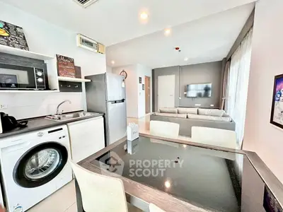 Modern open-plan living area with kitchen and dining space, featuring sleek appliances and stylish decor.