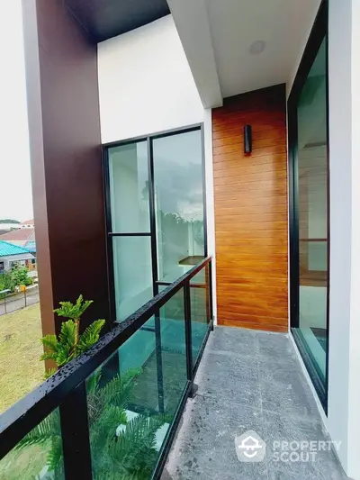 Modern balcony with glass railing and wooden paneling in a contemporary home.