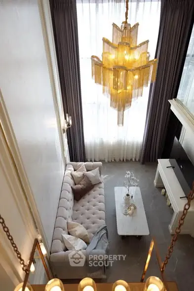 Luxurious high-ceiling living room with elegant chandelier and plush sofa, perfect for sophisticated living.