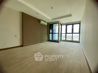 Spacious modern living room with large windows and city view, featuring sleek flooring and neutral tones.