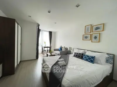 Modern bedroom with stylish decor and natural light, featuring a cozy seating area and elegant furnishings.