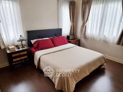 Cozy bedroom with elegant decor and natural light from large windows.