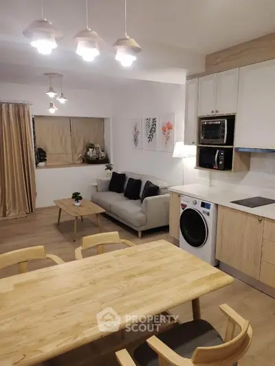 Modern open-plan living room with kitchen, featuring cozy sofa, dining table, and built-in appliances.