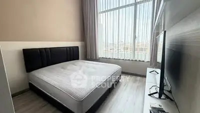 Modern bedroom with large window and stylish decor in a high-rise apartment.