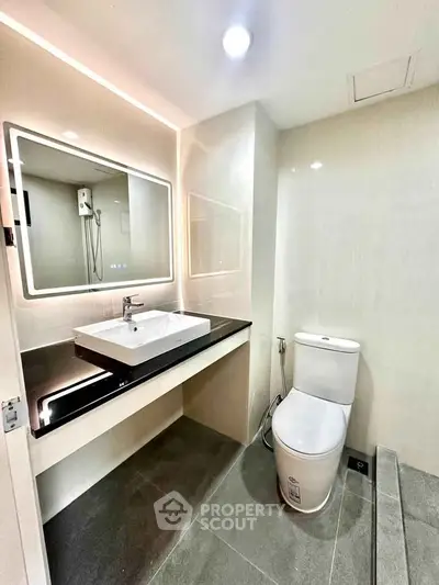 Modern bathroom with sleek fixtures and illuminated mirror in a contemporary apartment.