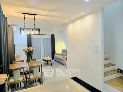 Modern open-plan living and dining area with elegant lighting and cozy seating.