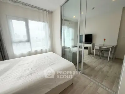 Modern apartment with bedroom and living room separated by glass sliding doors, featuring city views.