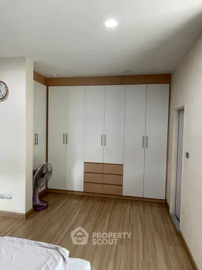 Spacious bedroom with built-in wardrobe and wooden flooring