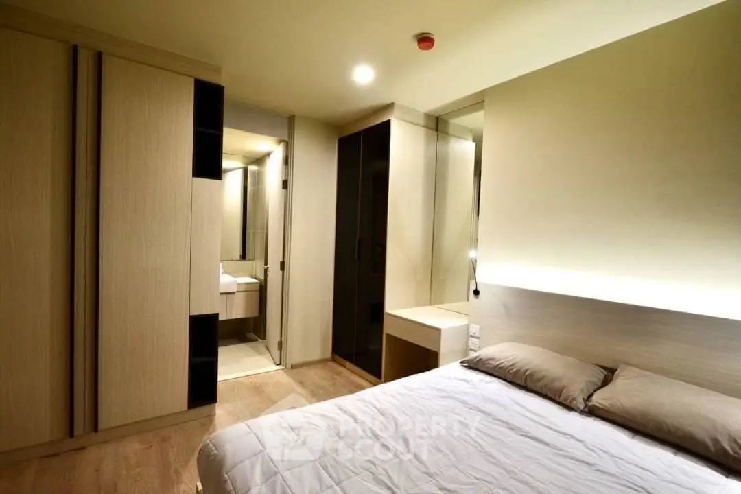 Modern bedroom with sleek design and ensuite bathroom, featuring built-in wardrobes and ambient lighting.