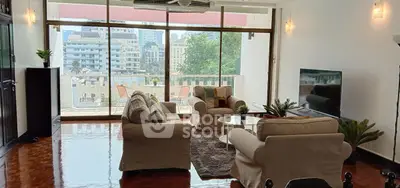 Spacious living room with large windows and city view, featuring cozy seating and modern decor.