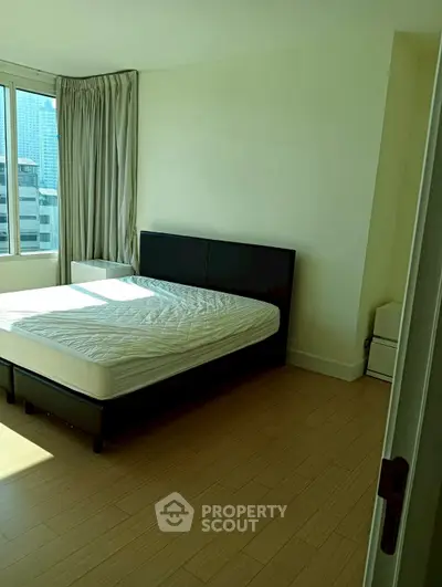 Spacious bedroom with large window and city view, featuring a modern bed and wooden flooring.