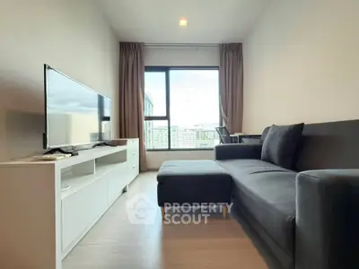 Modern living room with sleek furniture and large window offering city views.