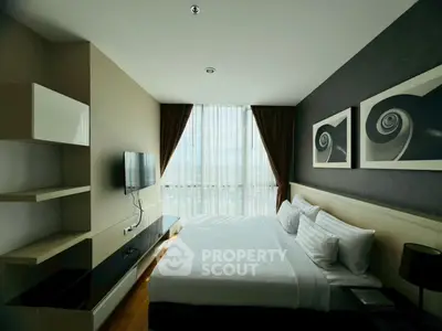 Modern bedroom with stylish decor and large window offering natural light and city view.