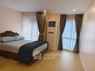 Spacious bedroom with modern decor and large windows for natural light.