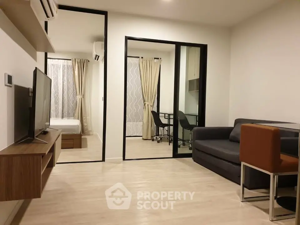 Modern apartment interior with open living room and bedroom, featuring sleek furniture and neutral tones.