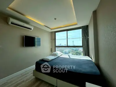 Modern bedroom with city view and wall-mounted TV in high-rise apartment.