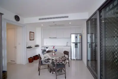 Modern kitchen with dining area, featuring sleek appliances and minimalist design.