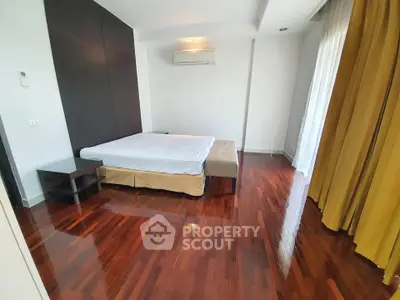 Spacious bedroom with polished wooden floors and modern decor