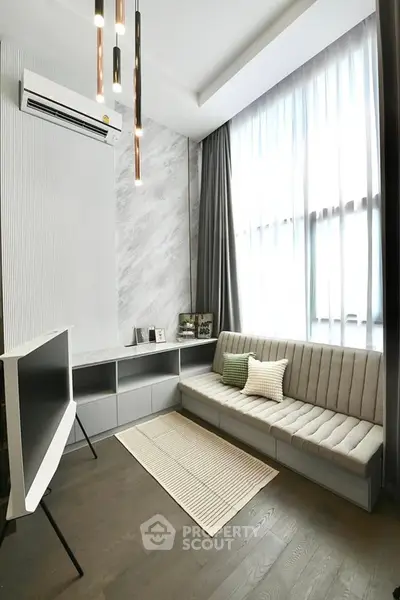 Modern living room with sleek design, featuring a cozy sofa, stylish lighting, and large window for natural light.