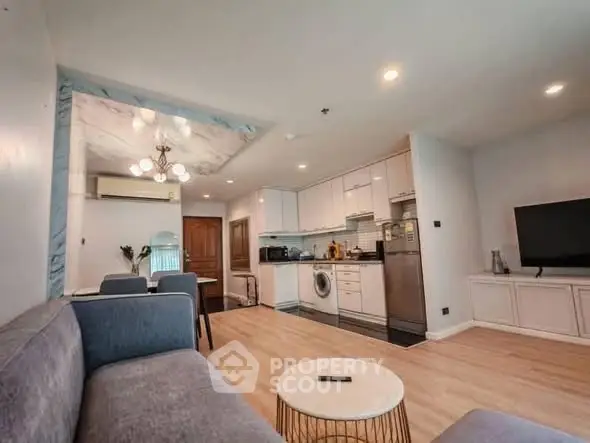 Modern open-plan living room with kitchen, featuring sleek appliances and cozy seating area.